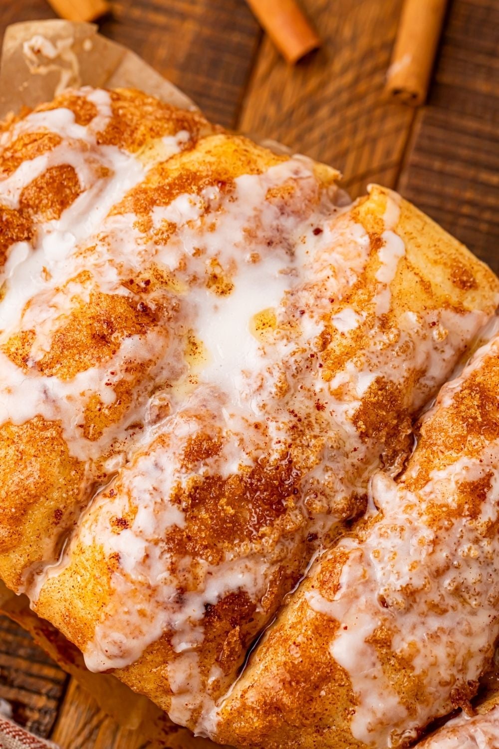 Dollywood Cinnamon Bread on a wooden table with cinnamon sticks around the table 