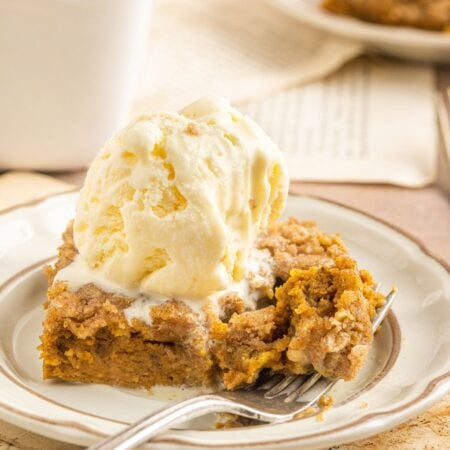 Homemade Pumpkin Crisp placed on a plate with ice cream on top of the crisp