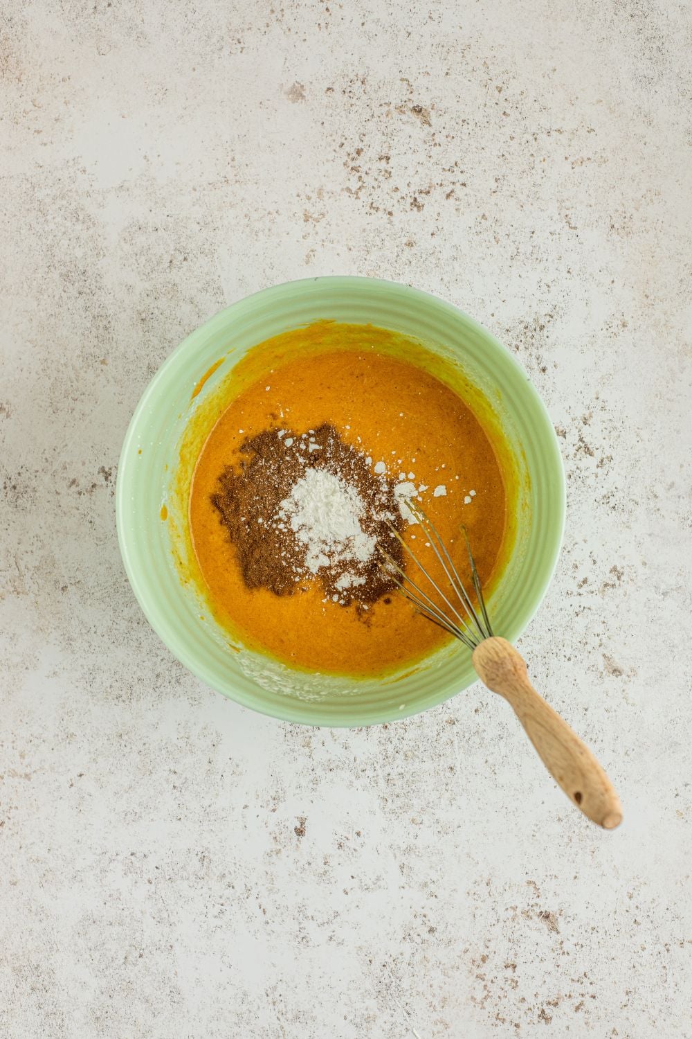 mixing up the pumpkin crumble batter in a green bowl on table 