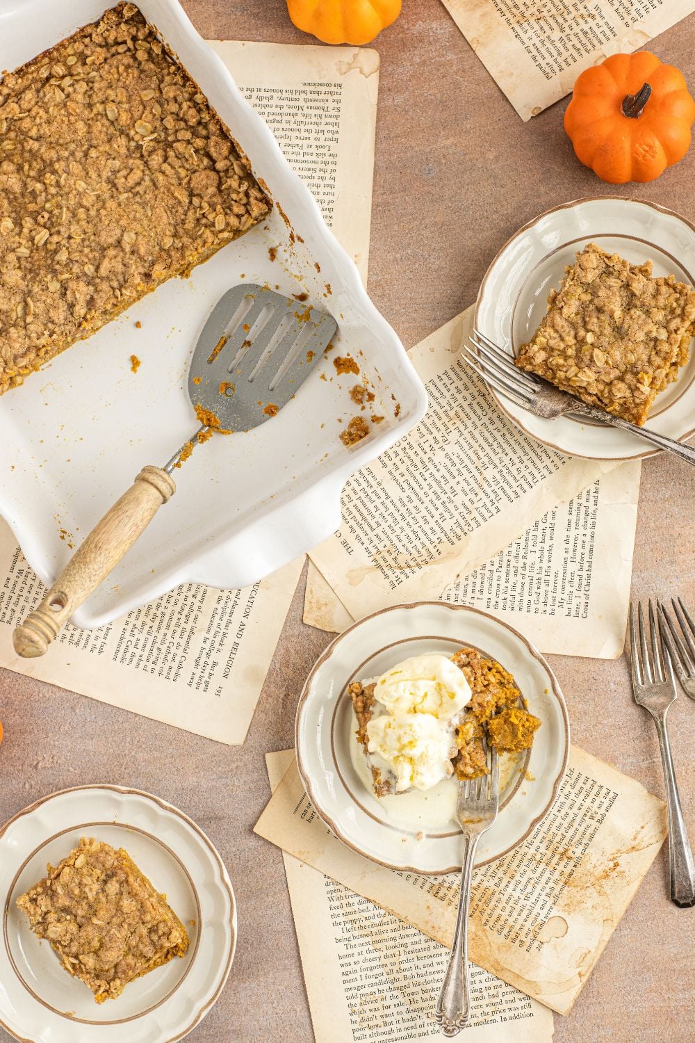 Homemade Pumpkin Crisp in a pan and plates placed around the table with slices on plates 