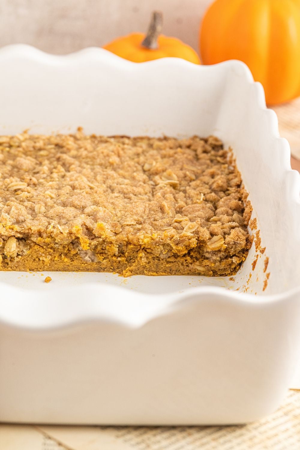 Homemade Pumpkin Crisp in a white casserole pan with some crisp taken out of the pan 